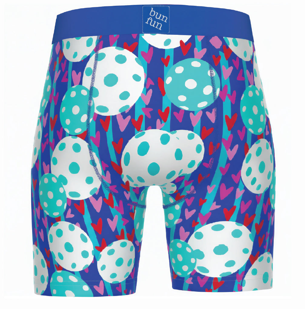 Men's boxer briefs featuring a vibrant pattern of white and teal polka-dot eggs, pink and red hearts, and teal stripes on a deep blue background. The waistband is solid blue with a white 'bun fun' brand label.