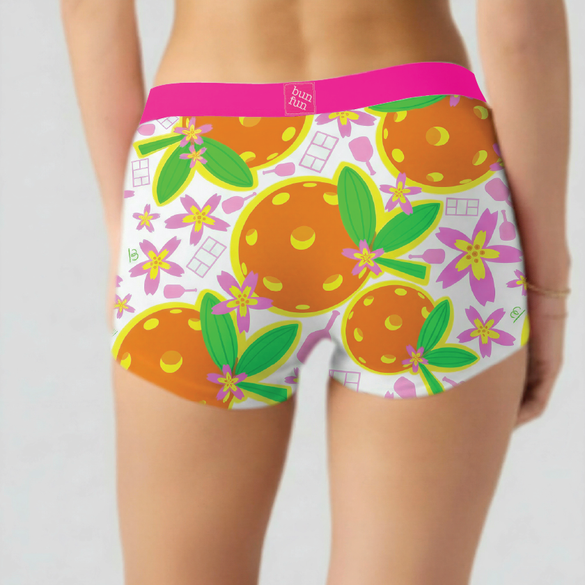 Person wearing colorful pickleball underwear with orange and floral pattern on a plain background