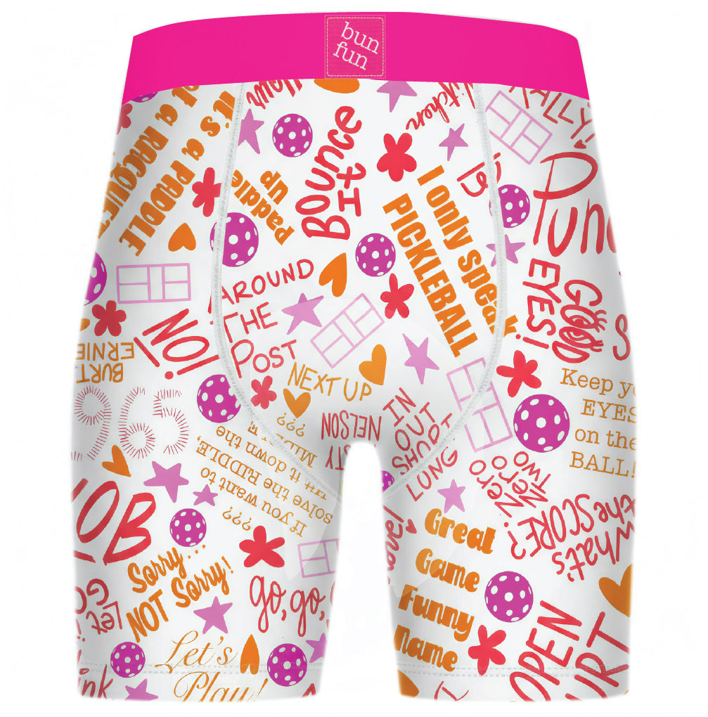 White boxer briefs with a bright pink waistband and an all-over multicolor retro-style graphic print featuring text, stars, hearts, and polka dots in pink, orange, and yellow.