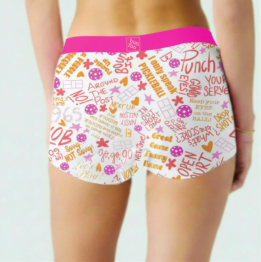 Moisture-wicking underwear for women with a bright pink waistband, featuring a colorful all-over text and graphic print, shown on a model from the back.